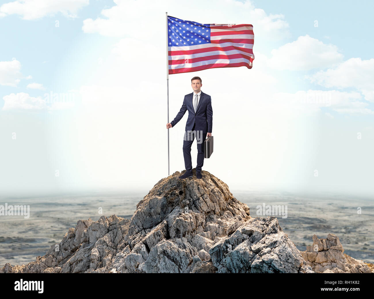 Successful businessman on the top of a mountain holding victory flag ...