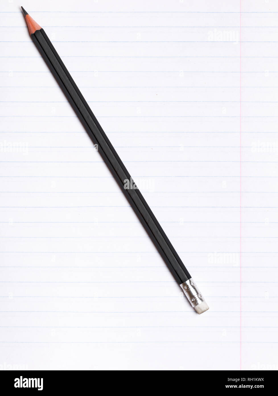 On a sheet of paper notebook with lines lies a black graphite pencil. Copy space. Education concept Stock Photo