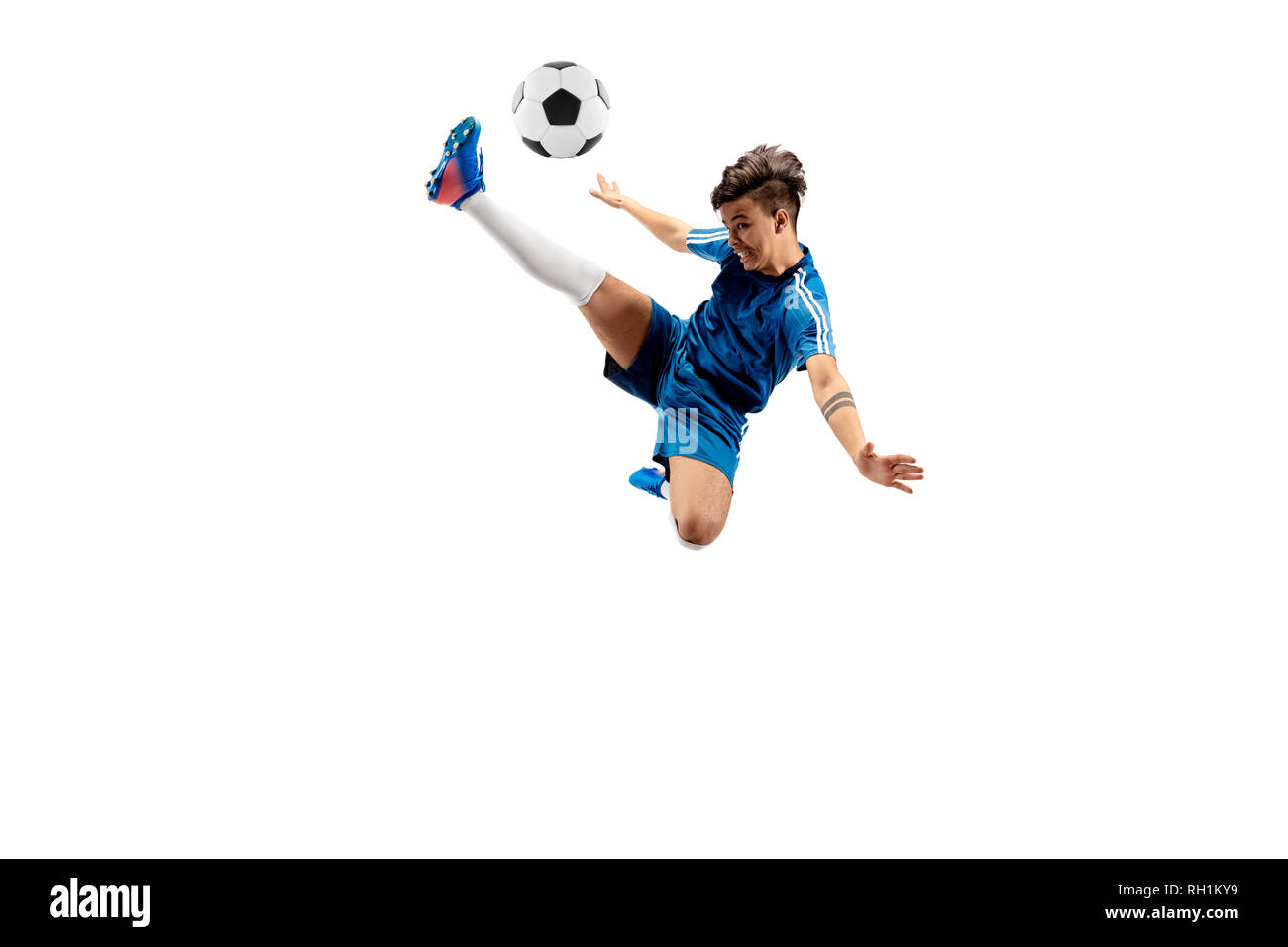 Young boy with soccer ball doing flying kick, isolated on white