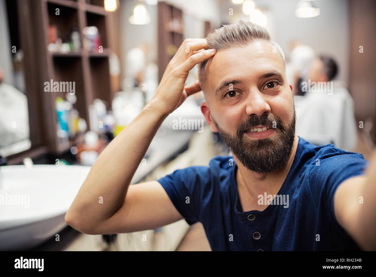 A hipster man client in barber shop, taking seflie. Copy space. Stock Photo