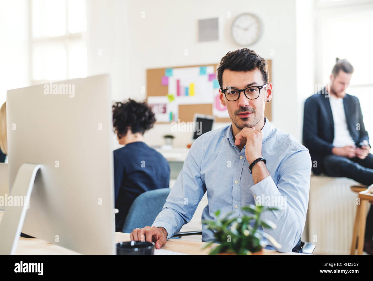 A portrait of young businessman with desktop computer working in a