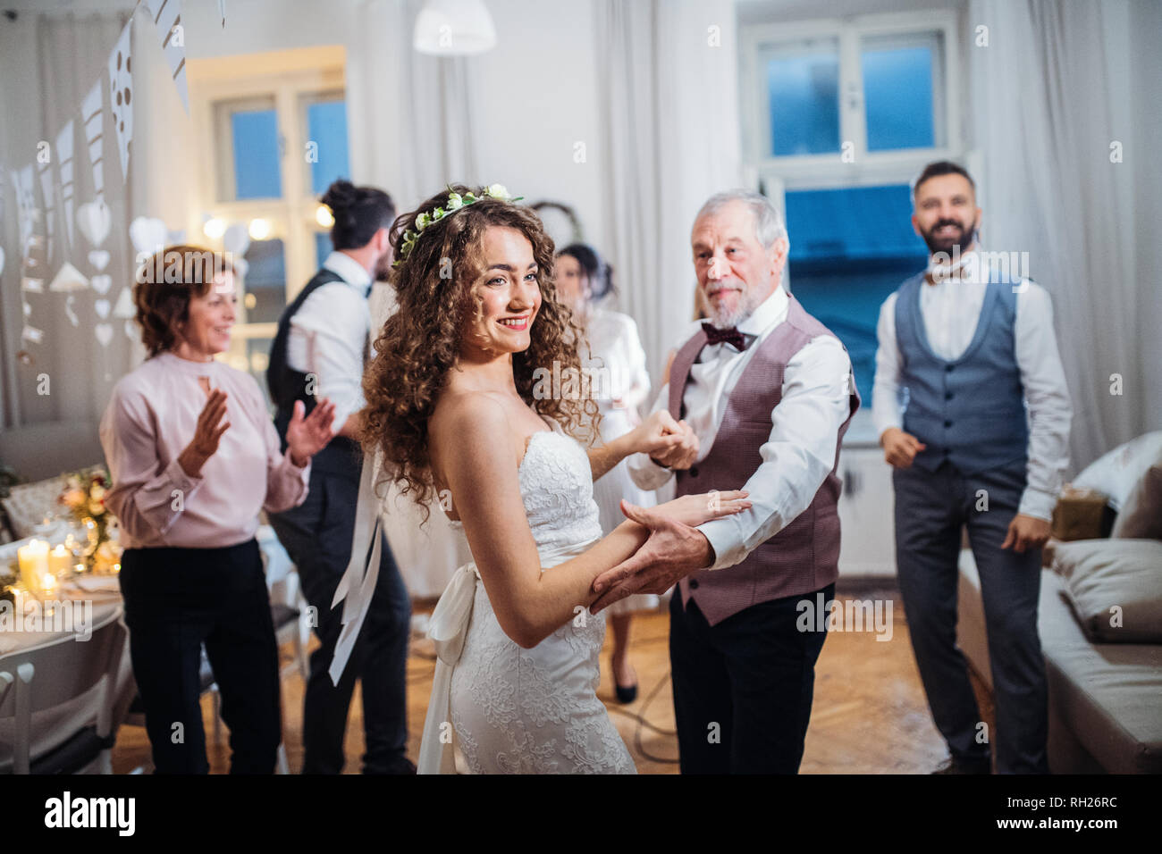 A young bride dancing with father or grandfather and other guests on a wedding reception. Stock Photo