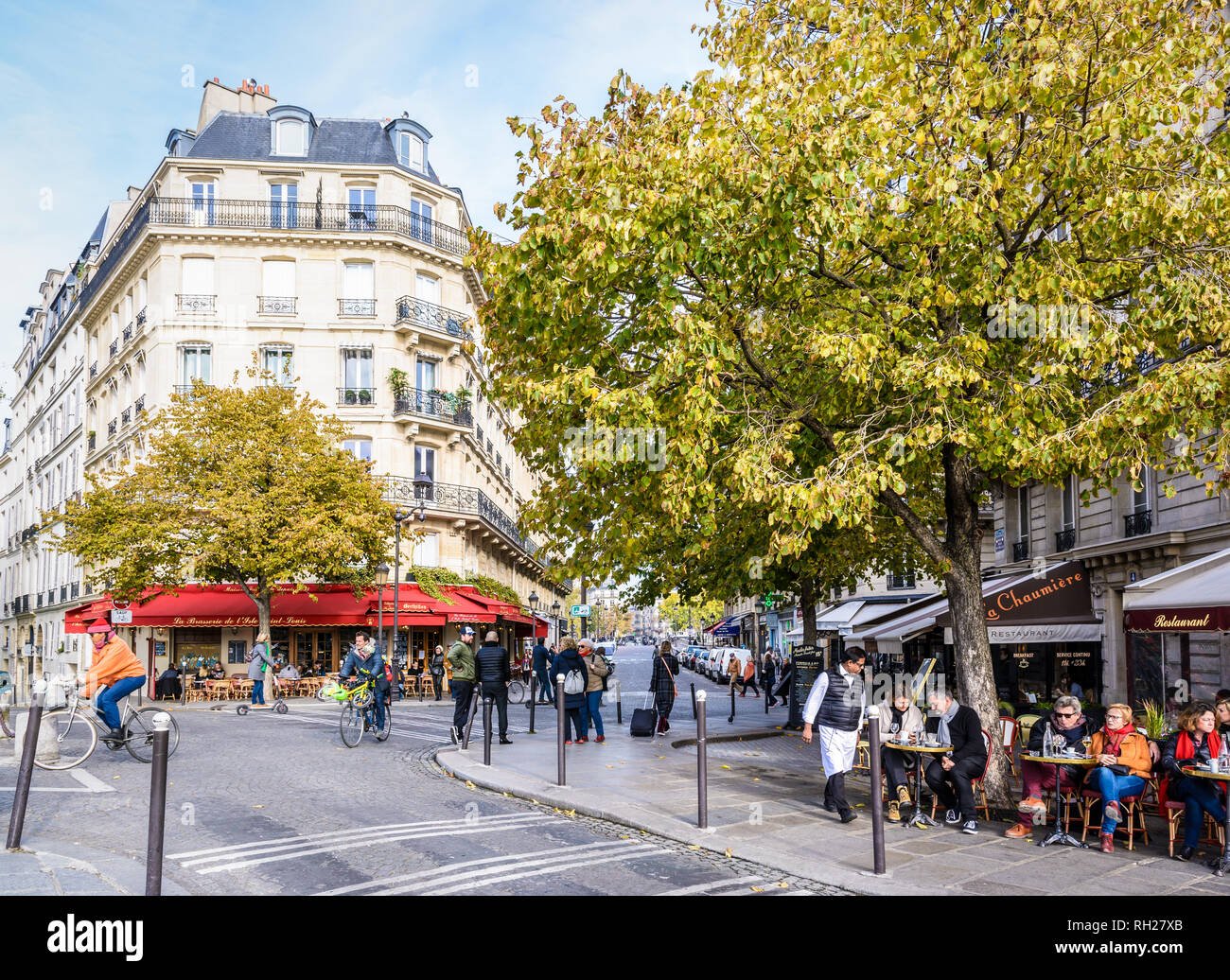 Typical scene on the ile Saint-Louis with people talking, strolling, biking or having a drink at the terrace of a cafe by a sunny autumn morning. Stock Photo