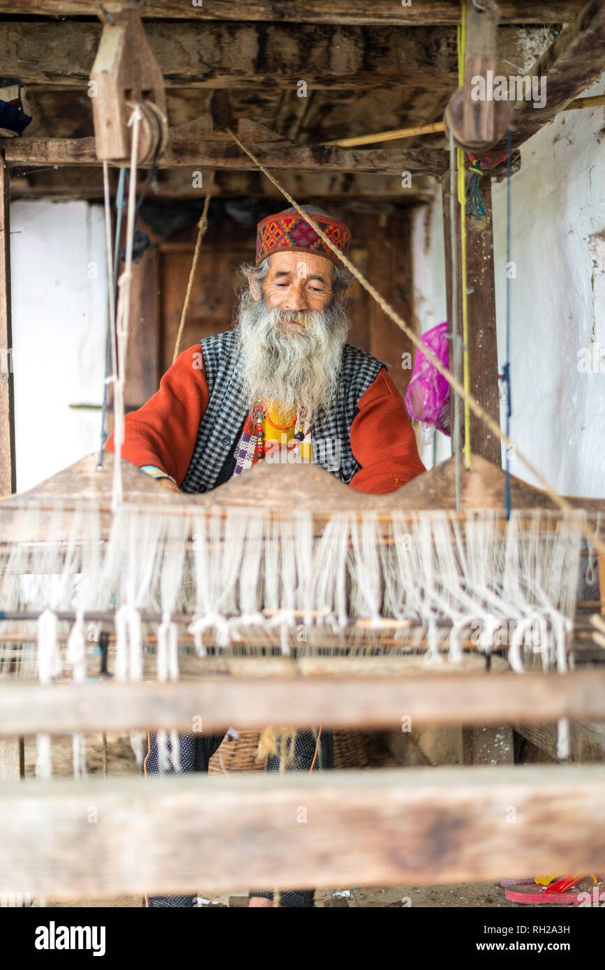 Kullu, Himachal Pradesh, India - August 09, 2018 : An Indian old man makes a traditional sadu weaving. Making A Pattu Sarees in Himalayas Stock Photo