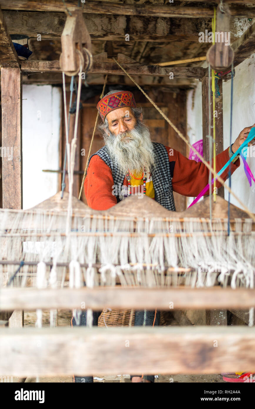 Kullu, Himachal Pradesh, India - August 09, 2018 : An Indian old man makes a traditional sadu weaving. Making A Pattu Sarees in Himalayas Stock Photo