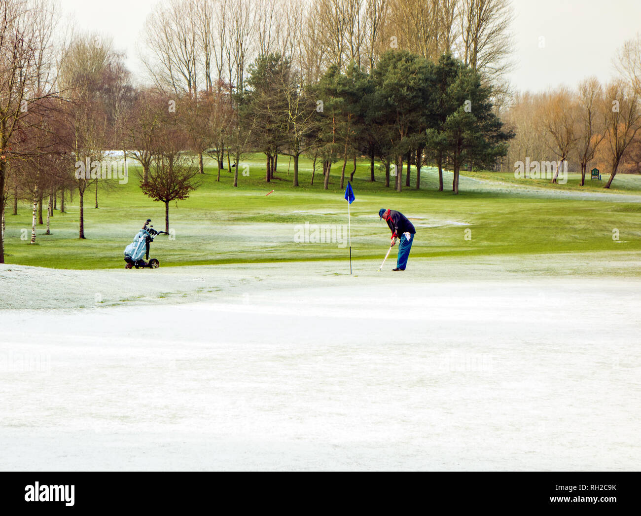 Man playing golf in winter on golf a course despite snow and freezing temperatures at Malkins