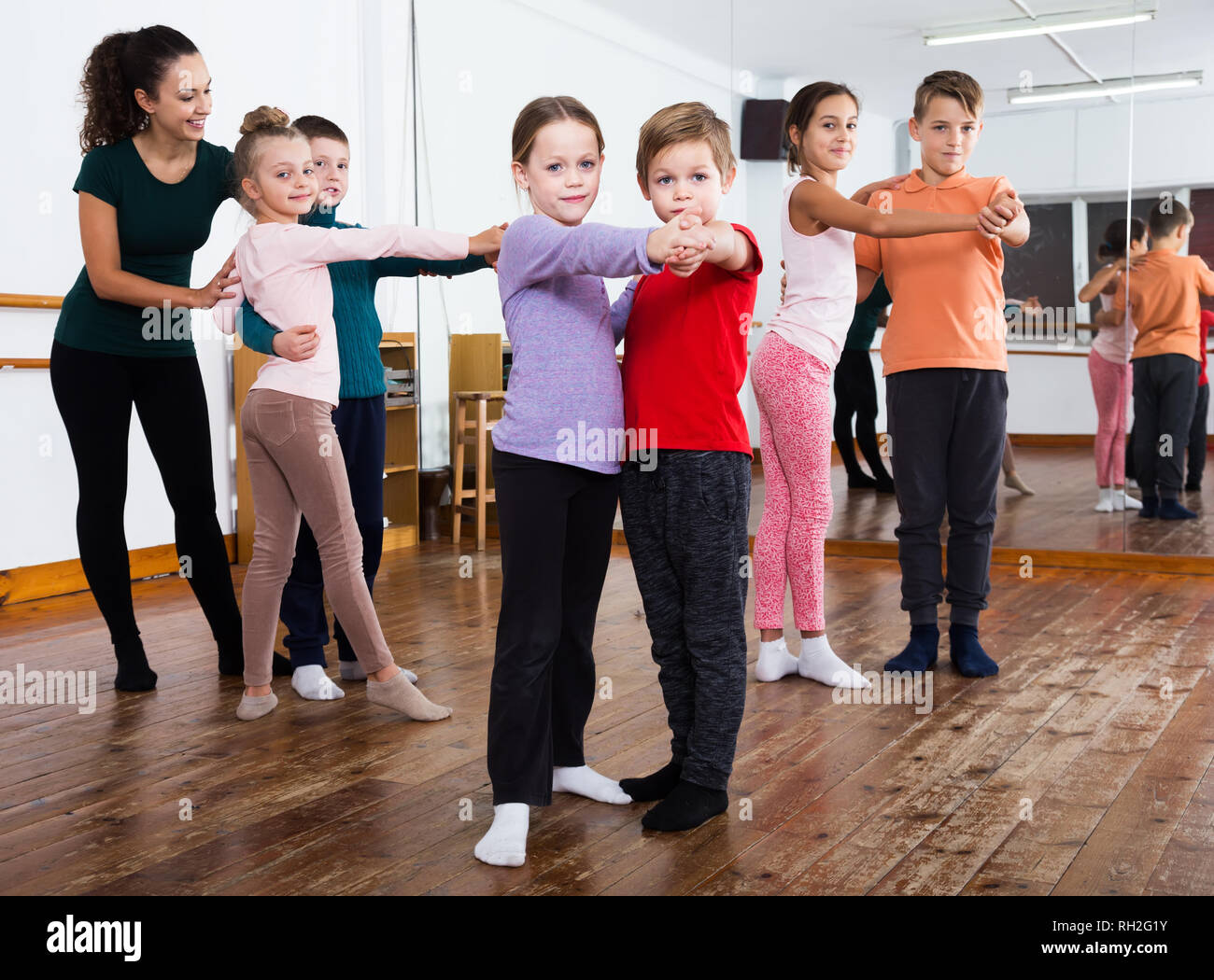 Group of children with female teacher dancing pair dance in dance class