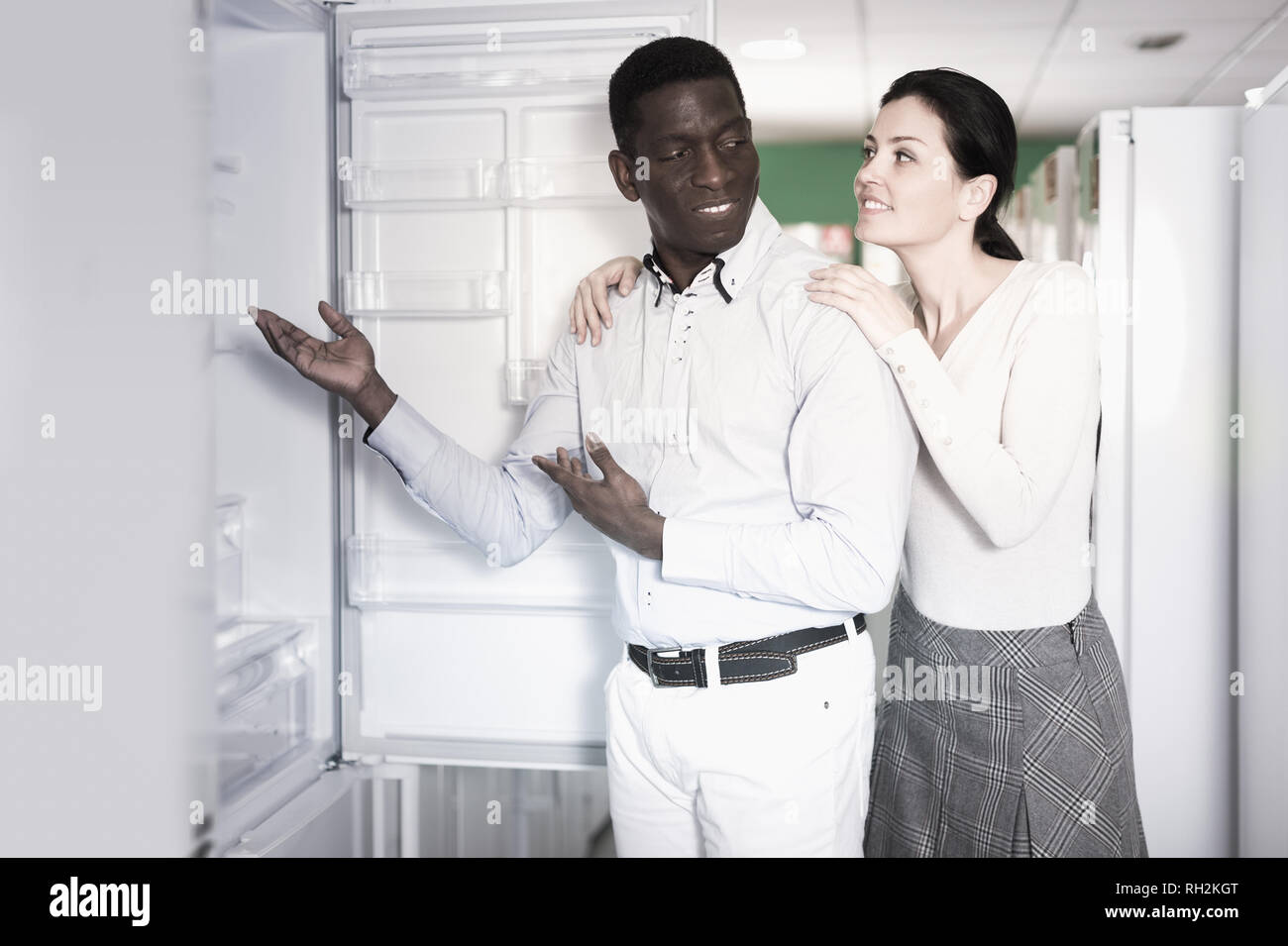 Interracial couple choosing fridge in store of household appliances Stock Photo