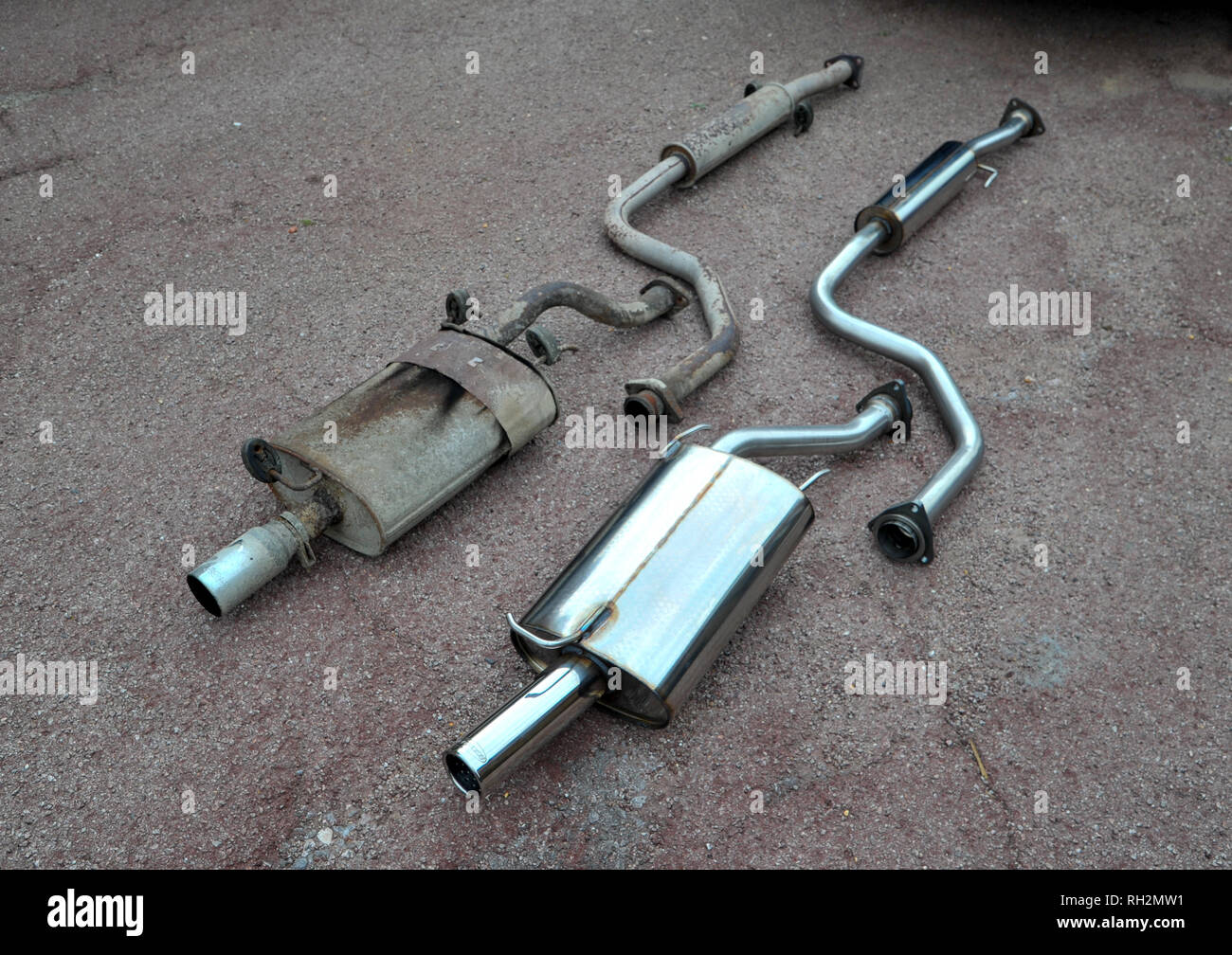 rusty old exhaust beside shiny stainless steel replacement Stock Photo