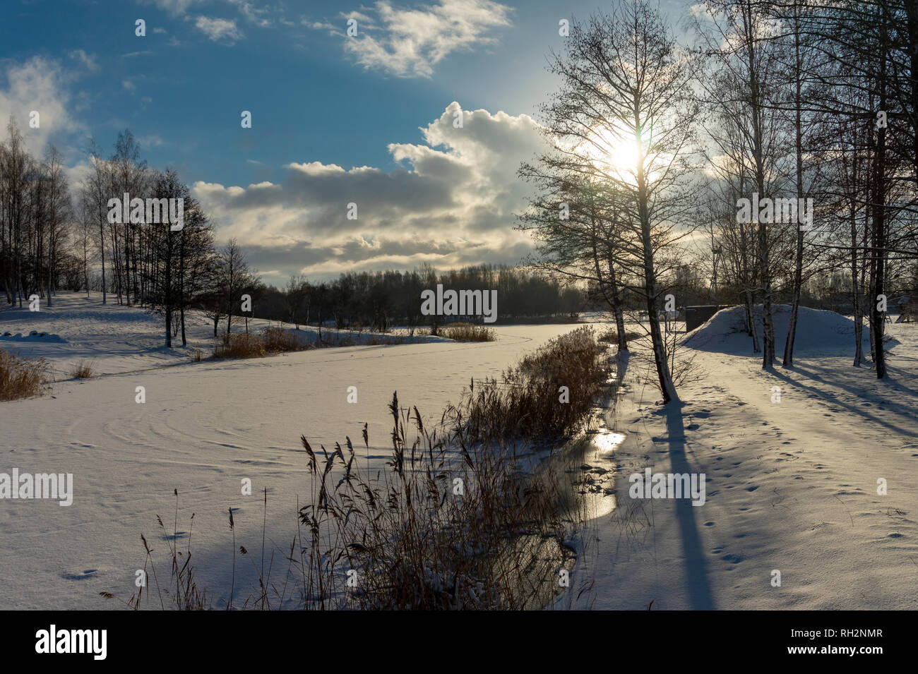 Frozen snow covered river in a winter landscape with sunburst through ...