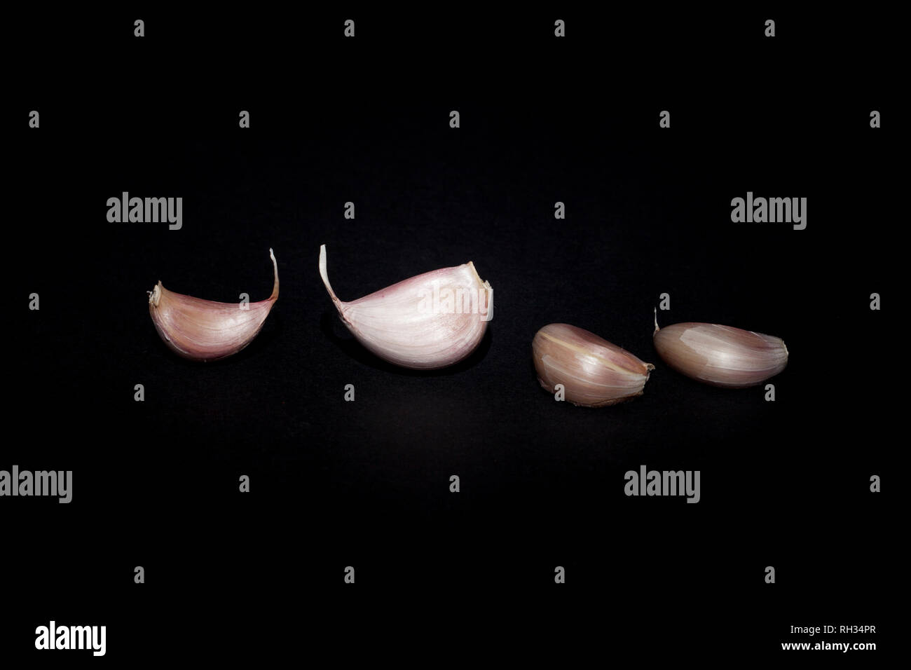 Garlic cloves on black background Stock Photo - Alamy