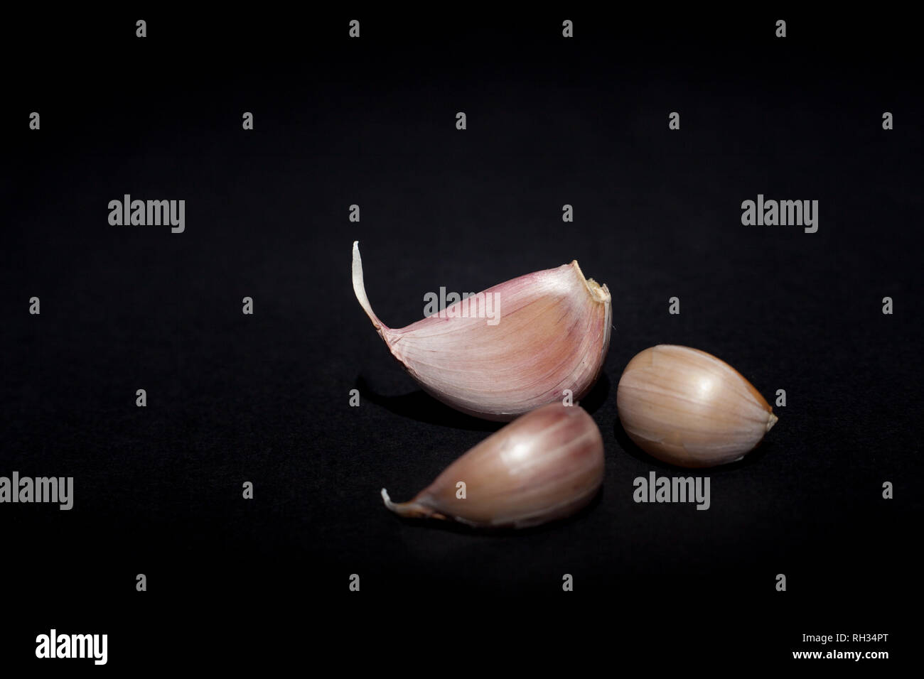 Garlic cloves on black background Stock Photo - Alamy