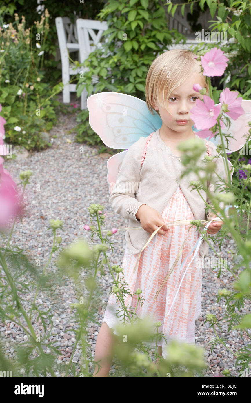 Girl wearing fairy wings in garden Stock Photo