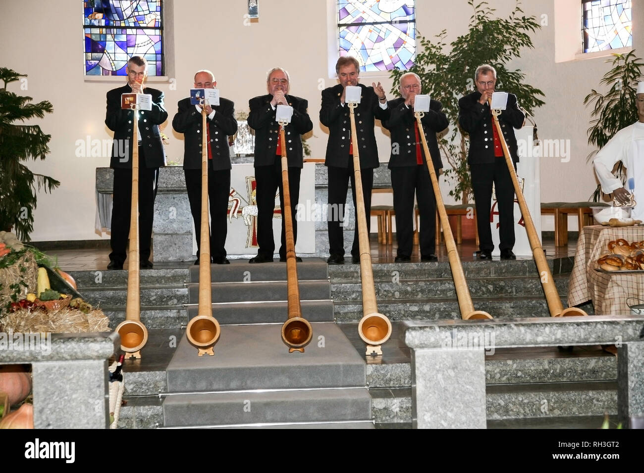 Six men in traditional outfits play the Alpenhorn in the local church for Thanksgiving in Sasbach, Germany, Black Forest. Stock Photo