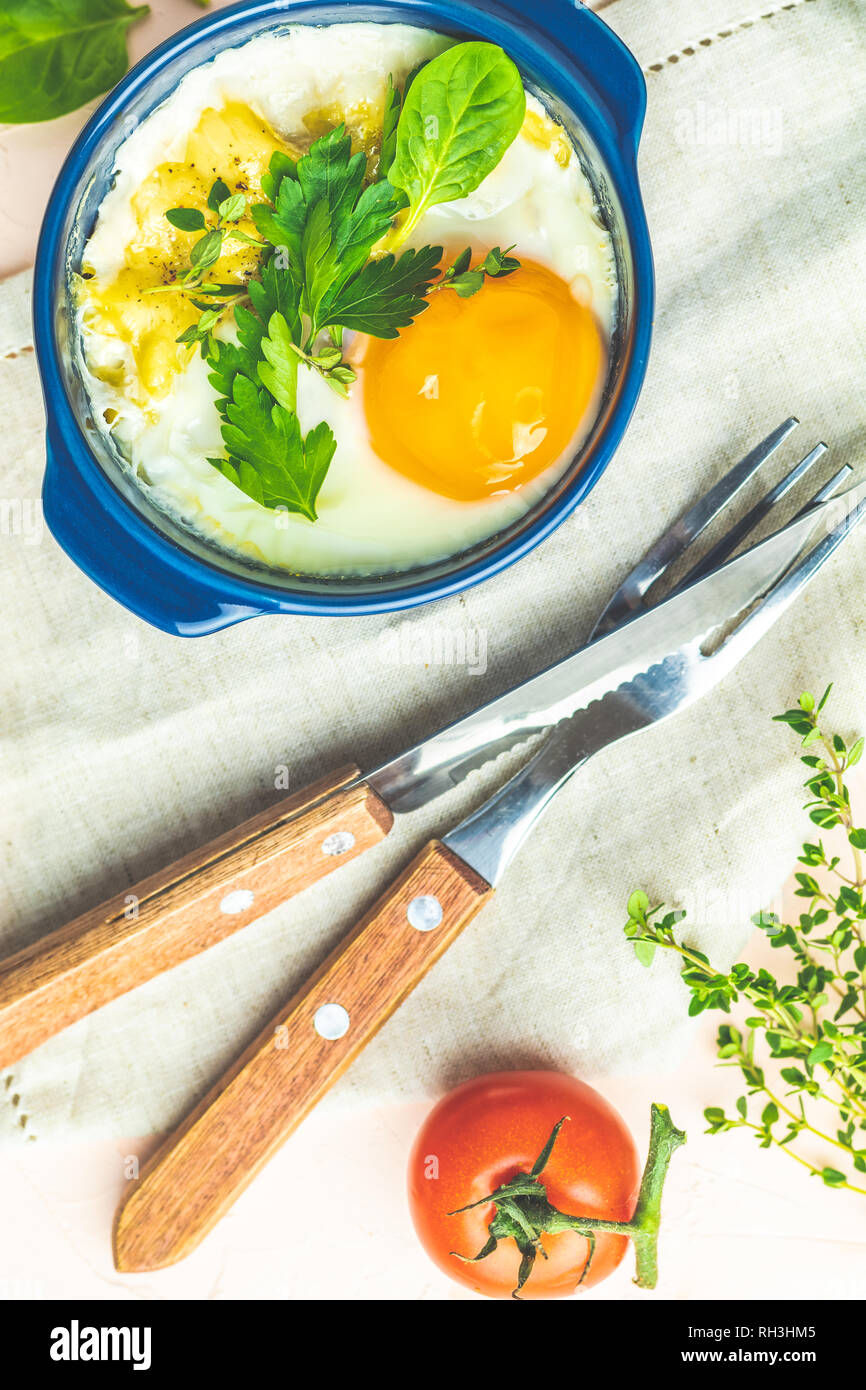Baked eggs in blue ceramic baking molds. Portioned casserole from