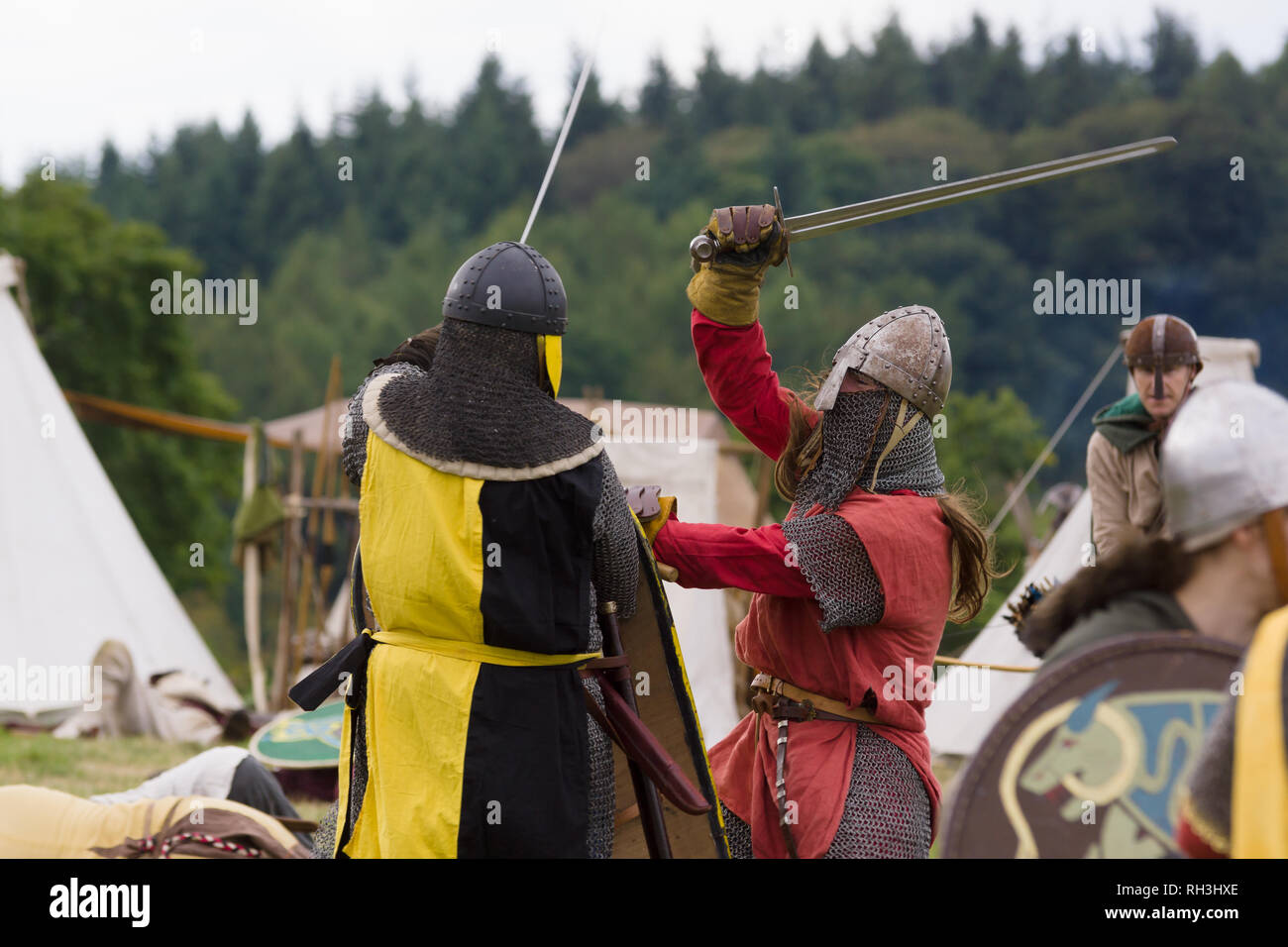 Medieval re-enactors dressed in armour and costumes of the 12th century equipped with swords and armour re-enacting combat of the period Stock Photo