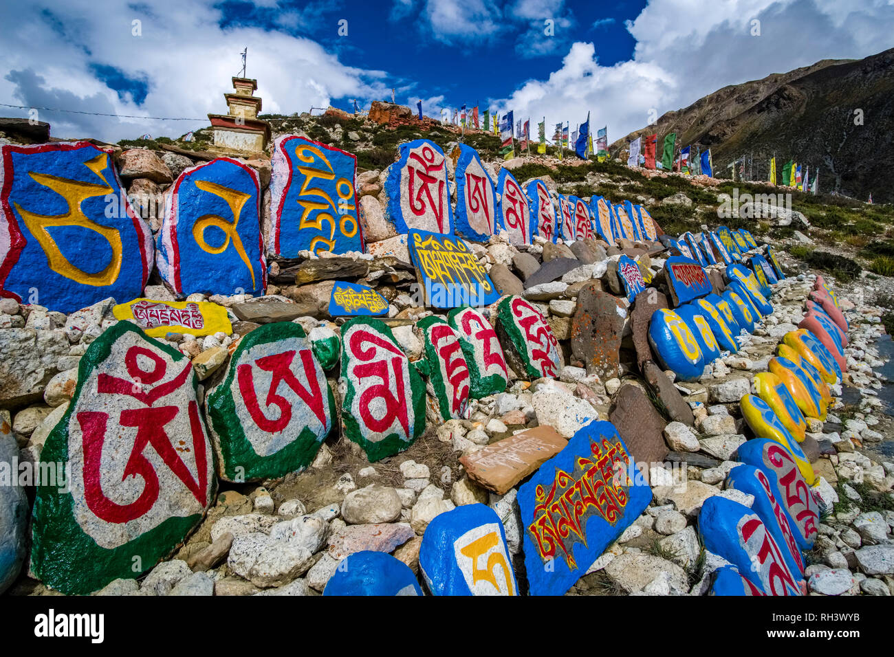 Many colorful Mani Stones with the rock carved buddhist mantra of Avalokiteshwara, the Om Mani Padme Hum, piled up around the local monastery Stock Photo