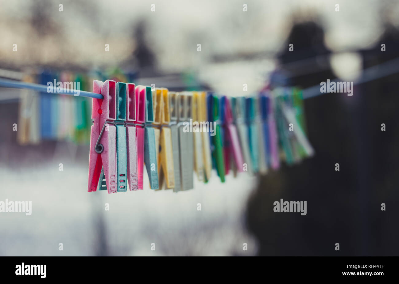 Beautiful colorful clothes pegs on the washing line with snow on background in winter. Stock Photo