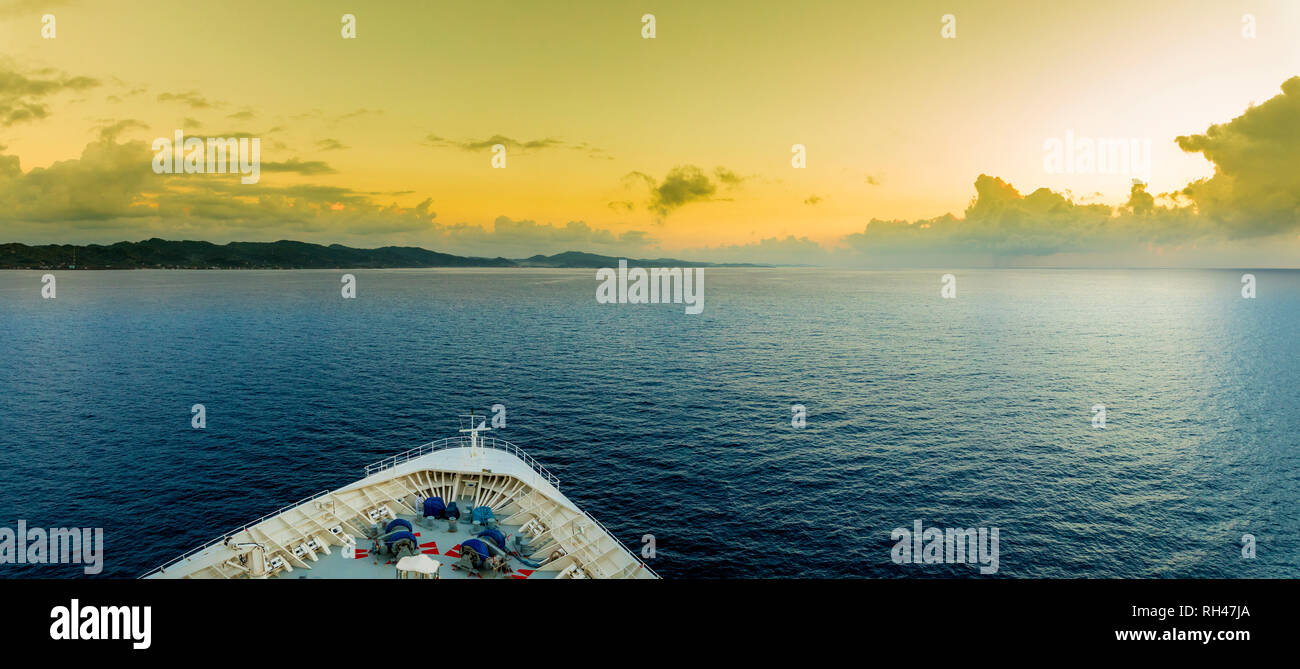 Panoramic view of the bow of a ship as it approaches the tropical island of Roatan. Stock Photo