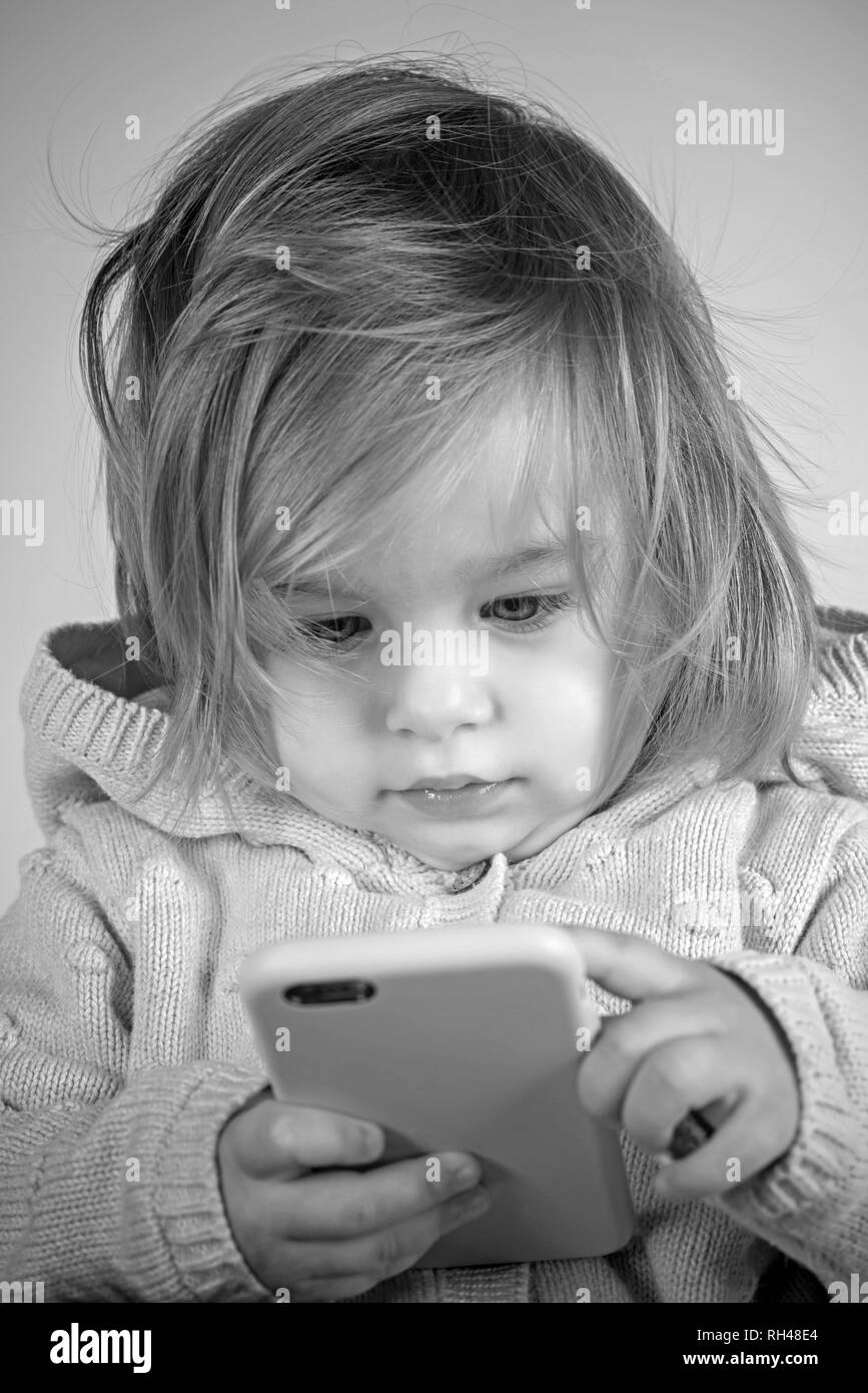 modern child play on phone. having fun. childhood and happiness. autumn and spring kid fashion. little girl child smiling. small happy girl. Capturing Stock Photo