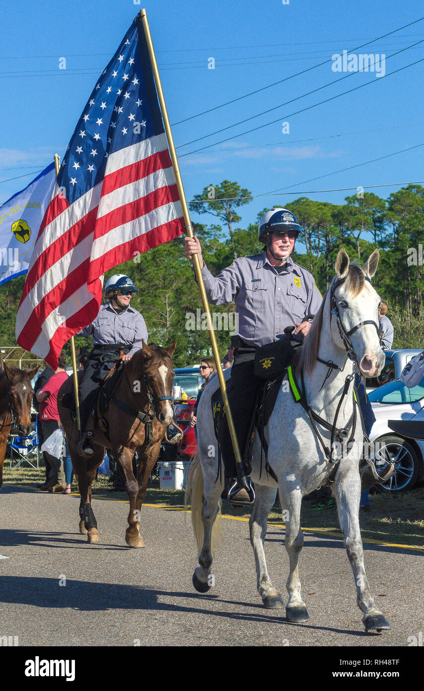 A mounted police officer carries an American flag during the Krewe de la Dauphine parade in Dauphin Island, Alabama, Jan. 17, 2015. Stock Photo