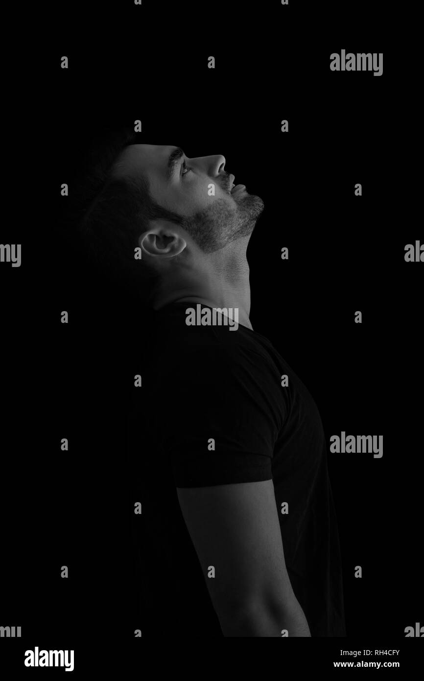 portrait of man while looking up Against Black Background Stock Photo
