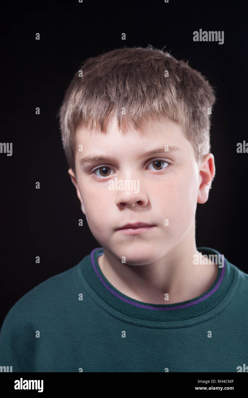 Studio shots of young boy with short brown hair, wearing green jumper Stock Photo