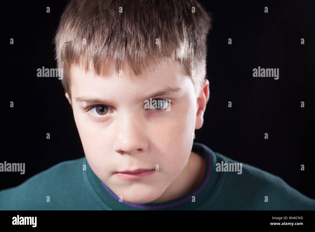 Studio shots of young boy with short brown hair, wearing green jumper Stock Photo