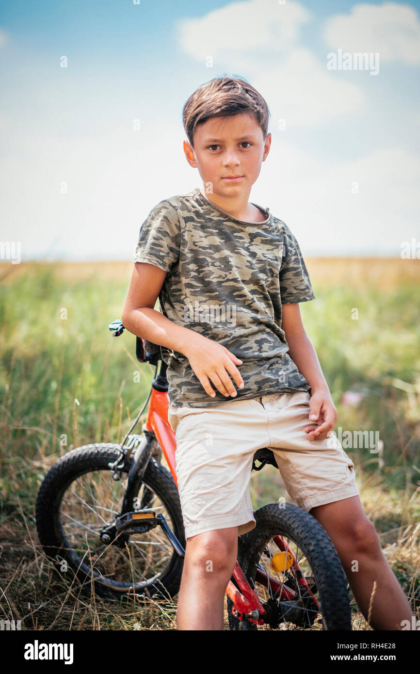 Portrait serious boy on bicycle in field Stock Photo