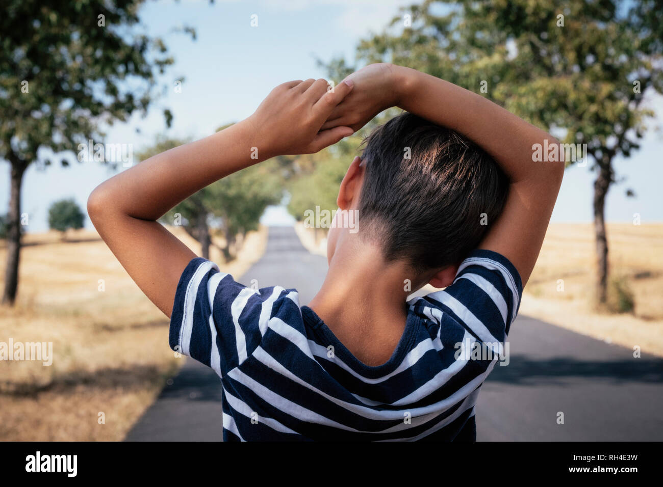 Boy standing on rural road Stock Photo