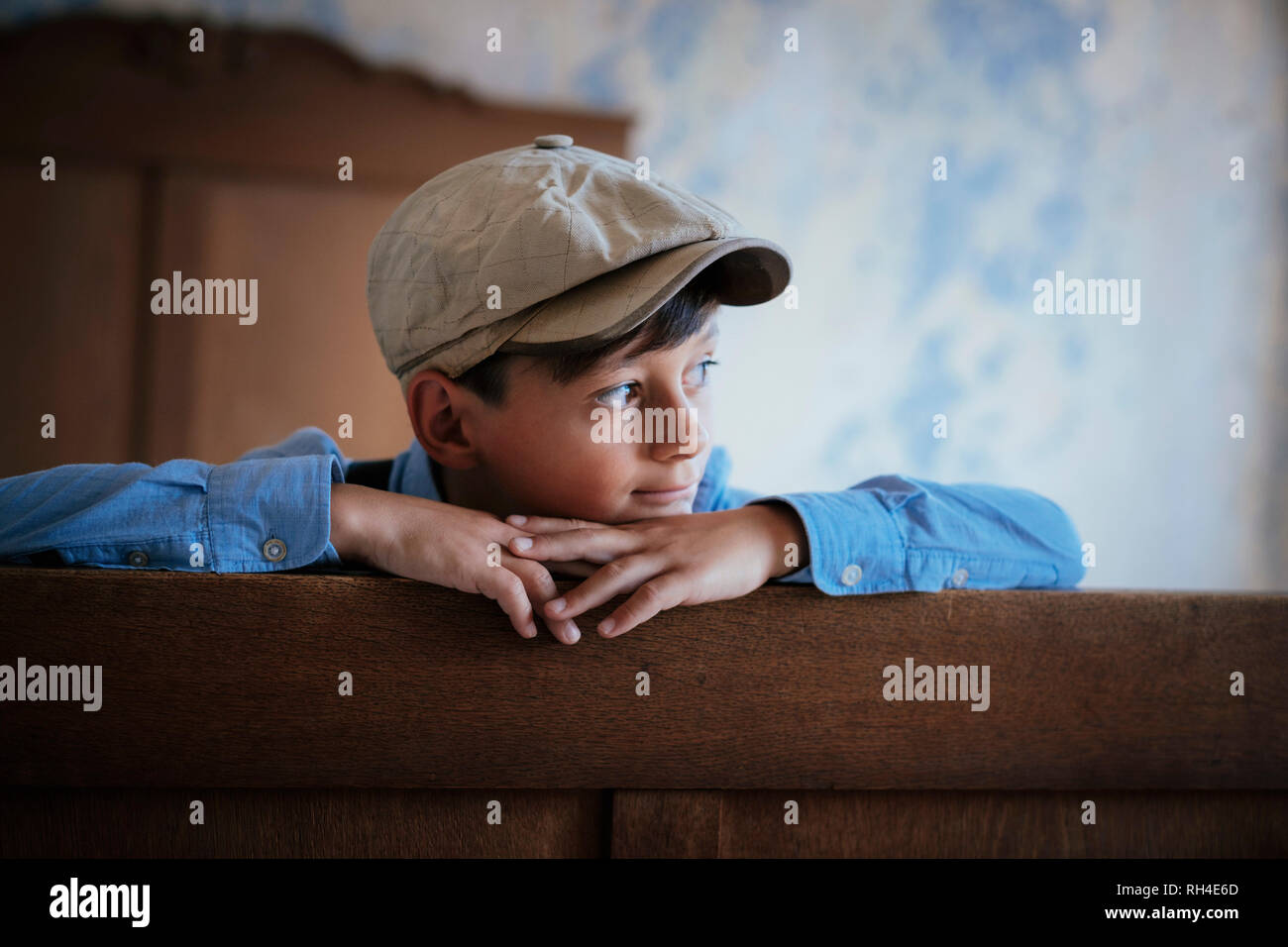 Thoughtful boy in cap looking away on bed Stock Photo