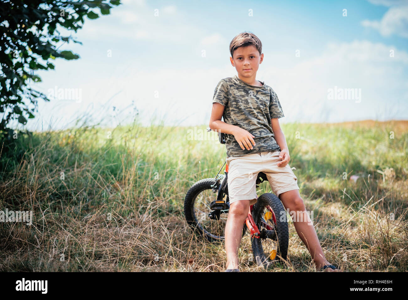 Portrait confident boy on bicycle in rural field Stock Photo