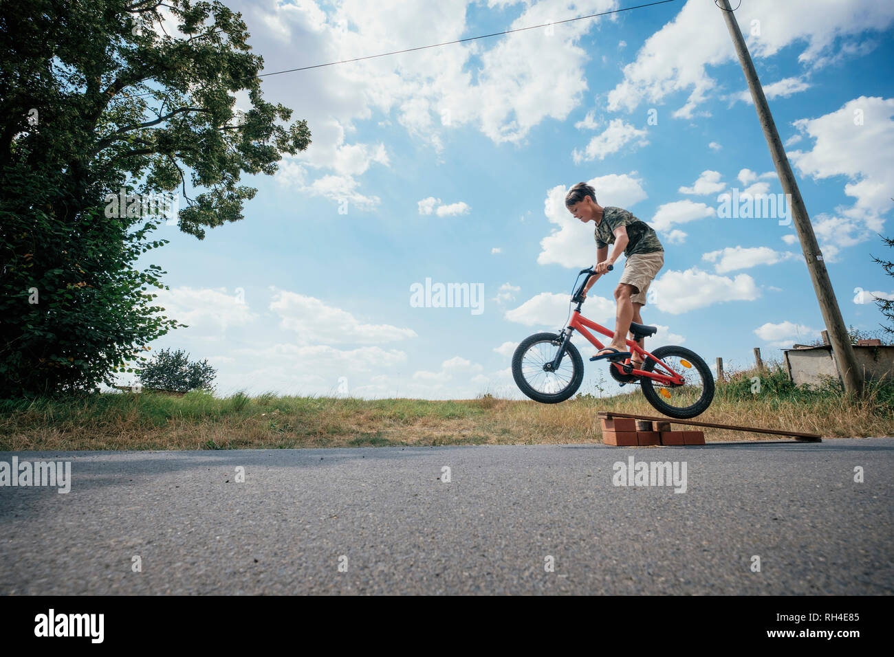 Boy riding bicycle off ramp Stock Photo