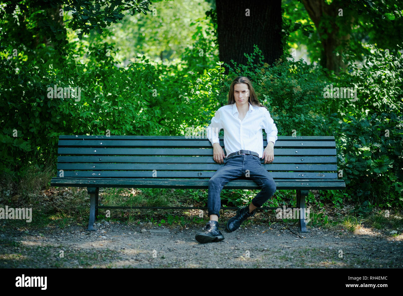 Portrait confident young man sitting on park bench Stock Photo