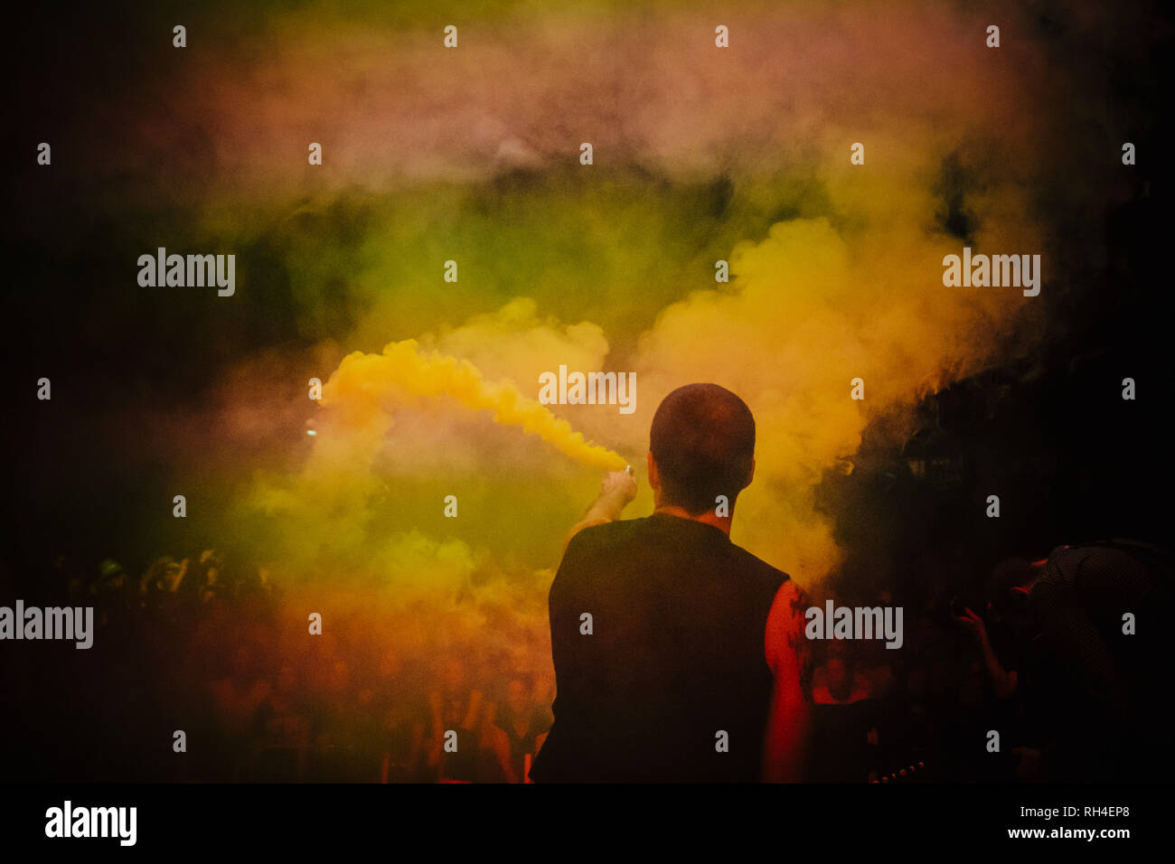 Male DJ on stage holding smoke bomb Stock Photo