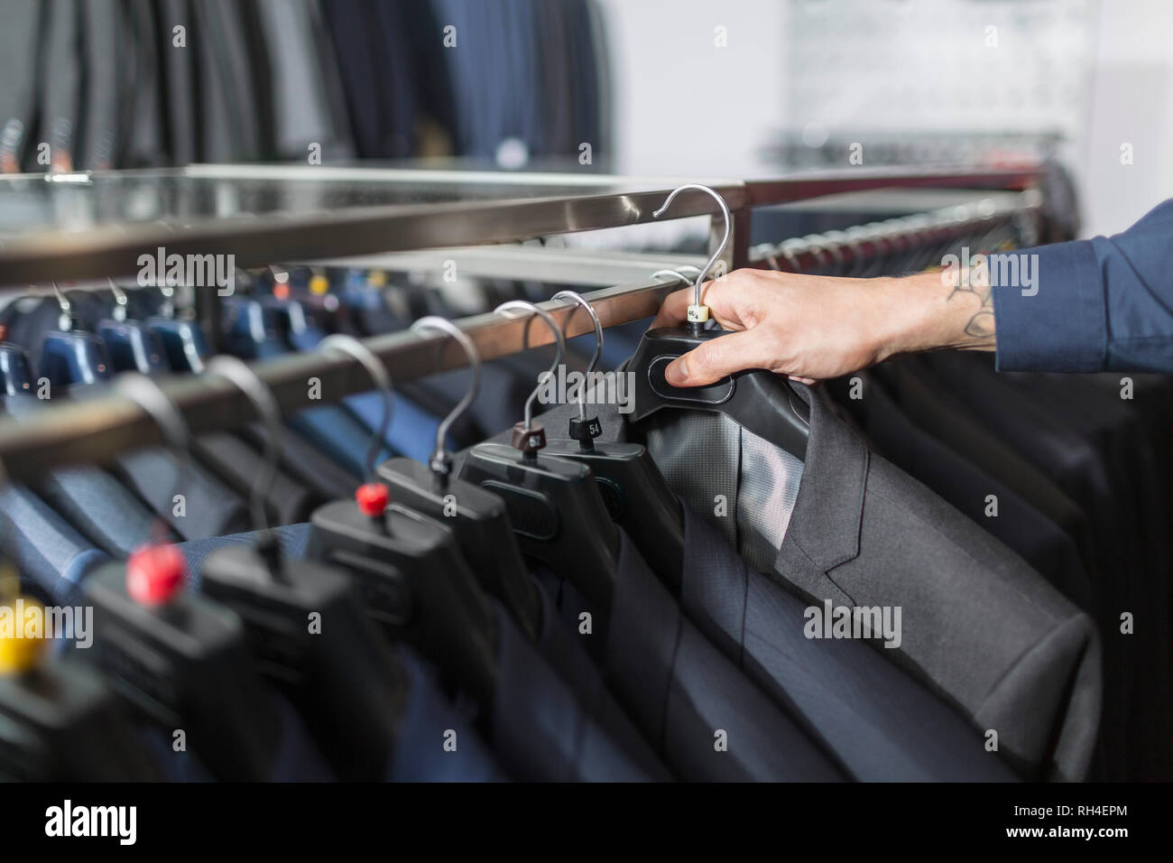 Man reaching for suit on hanger in menswear shop Stock Photo