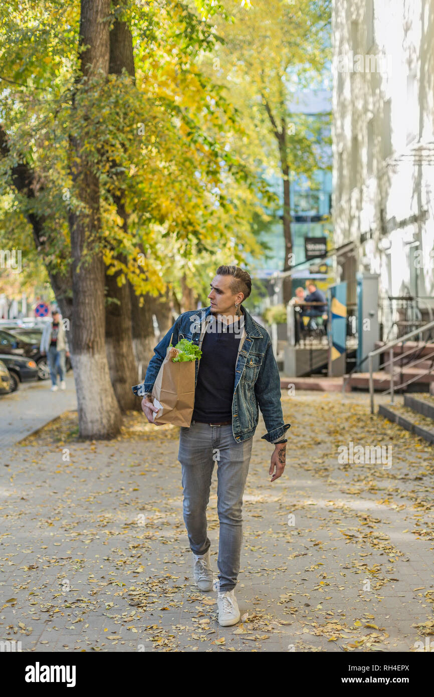 Man carrying groceries on autumn sidewalk Stock Photo
