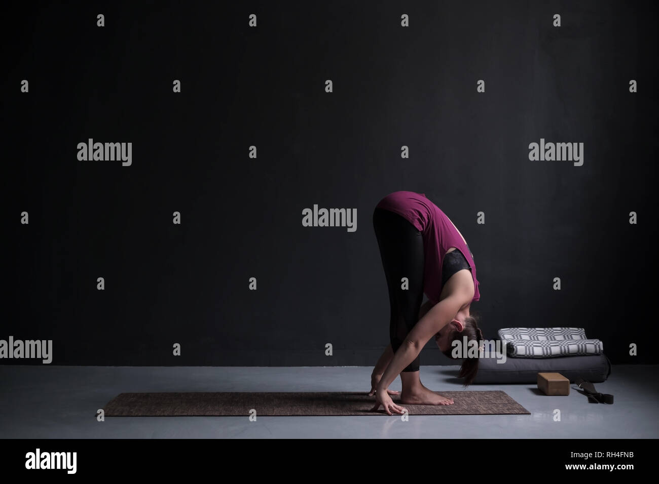 Sporty woman practicing yoga, standing forward bend exercise, uttanasana pose. Stock Photo