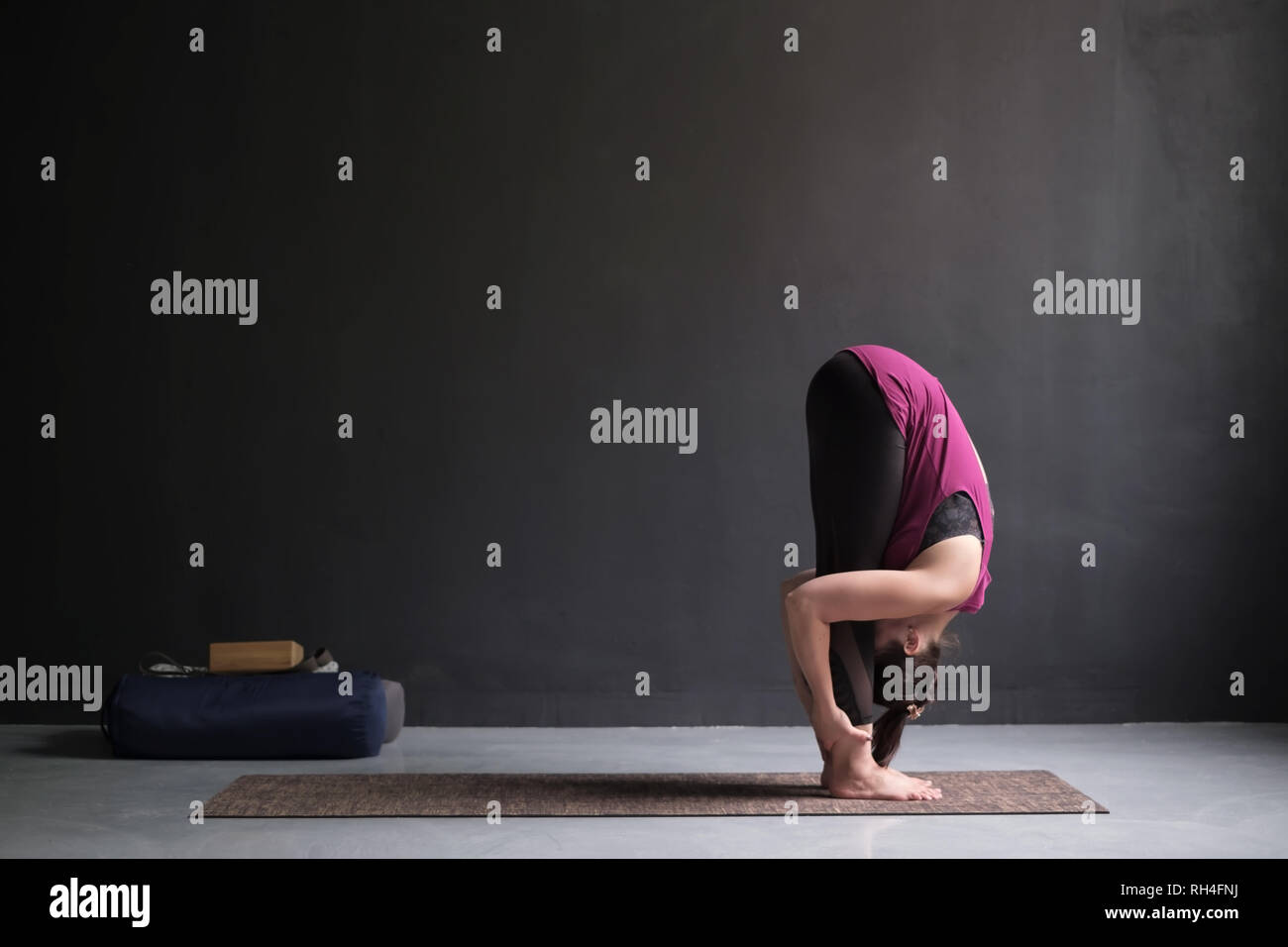 Sporty woman practicing yoga, standing forward bend exercise, uttanasana pose. Stock Photo