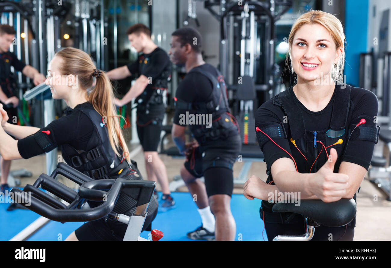 Athletic young positive girl during electric muscle stimulation workout in fitness gym Stock