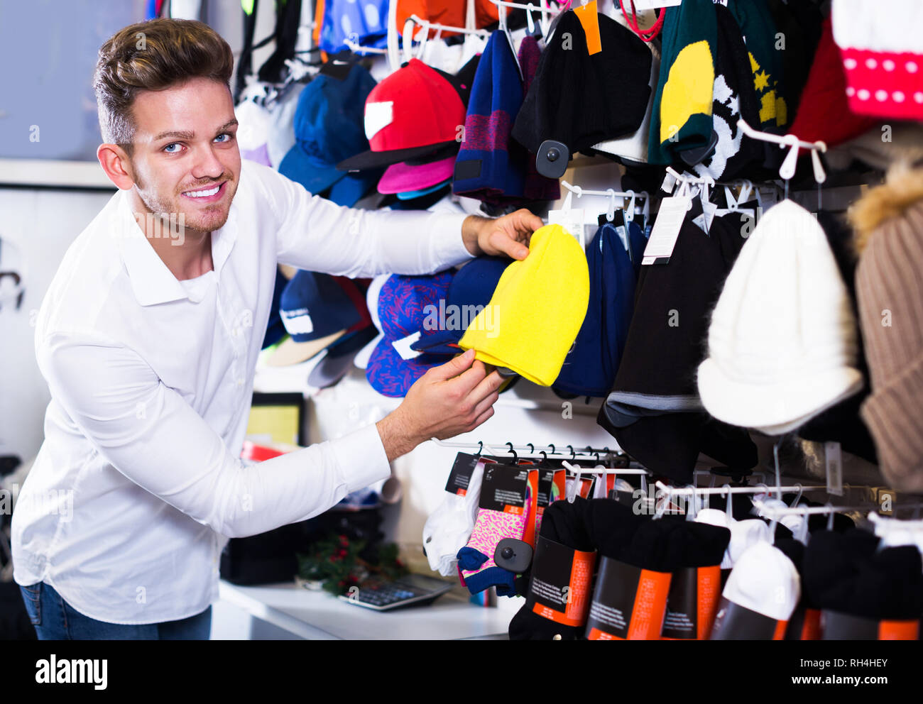Young man choosing new knit cap in sports store Stock Photo