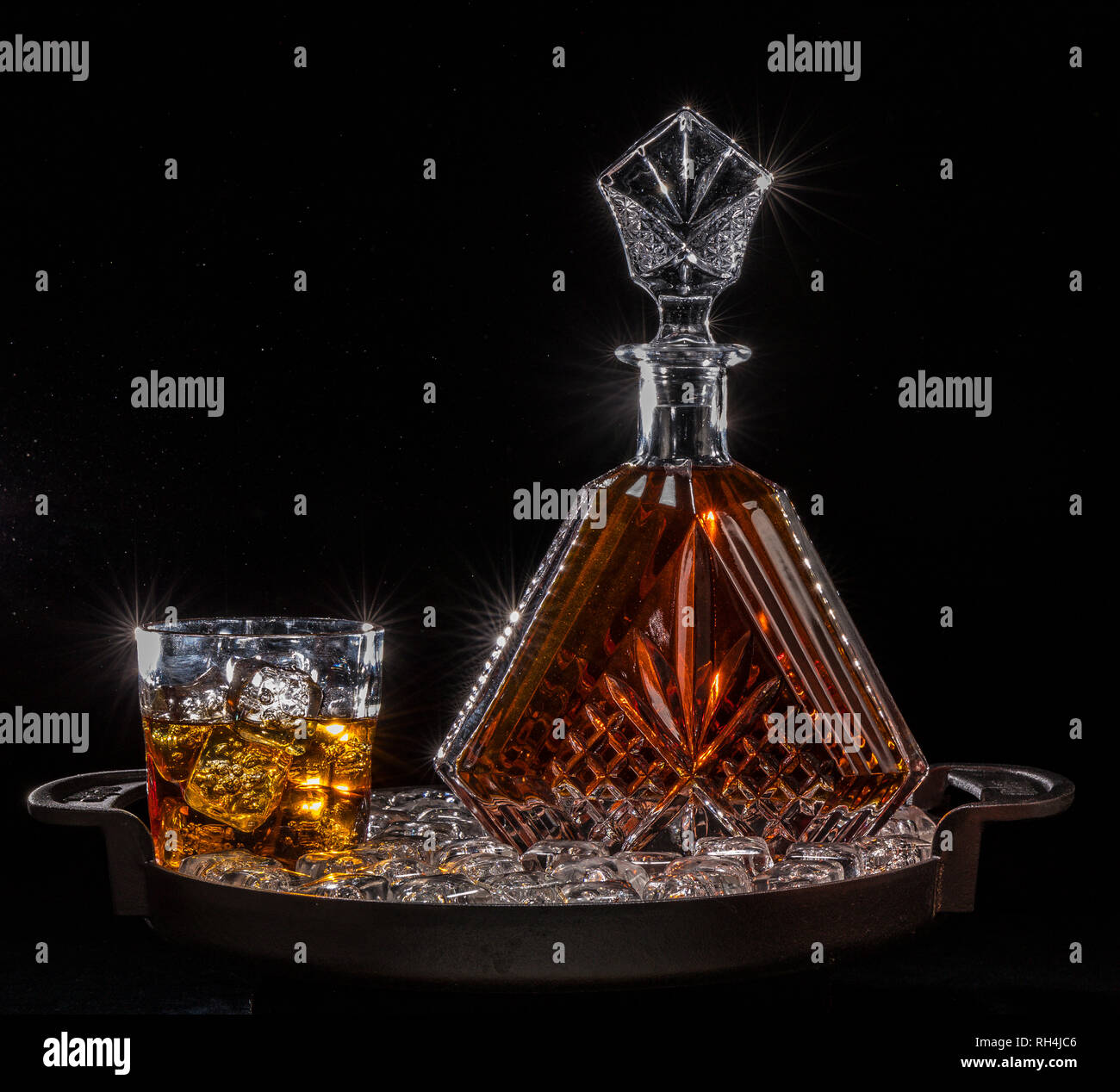 liquor decanter and glass on cast iron serving tray with ice cubes