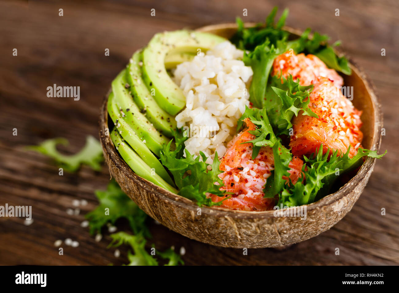 Hawaiian poke coconut bowl with grilled salmon fish, rice and avocado