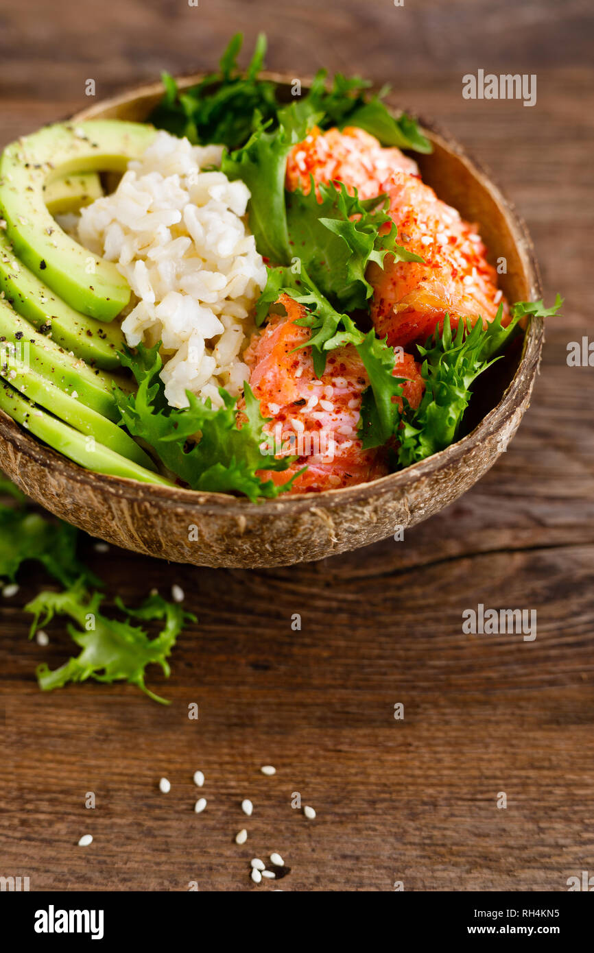 Hawaiian poke coconut bowl with grilled salmon fish, rice and avocado