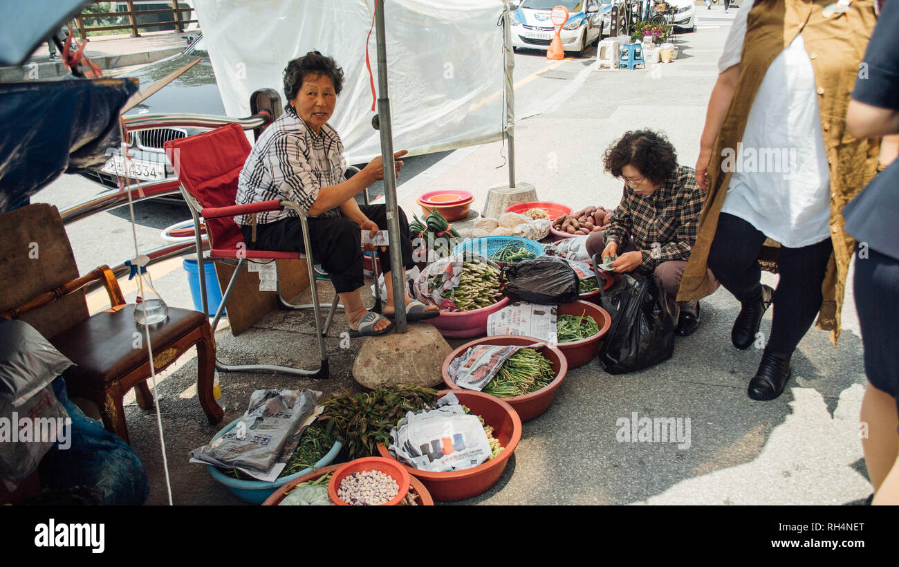 Elderly woman selling produce on the street to a middle-aged woman in Seoul, South Korea Stock Photo