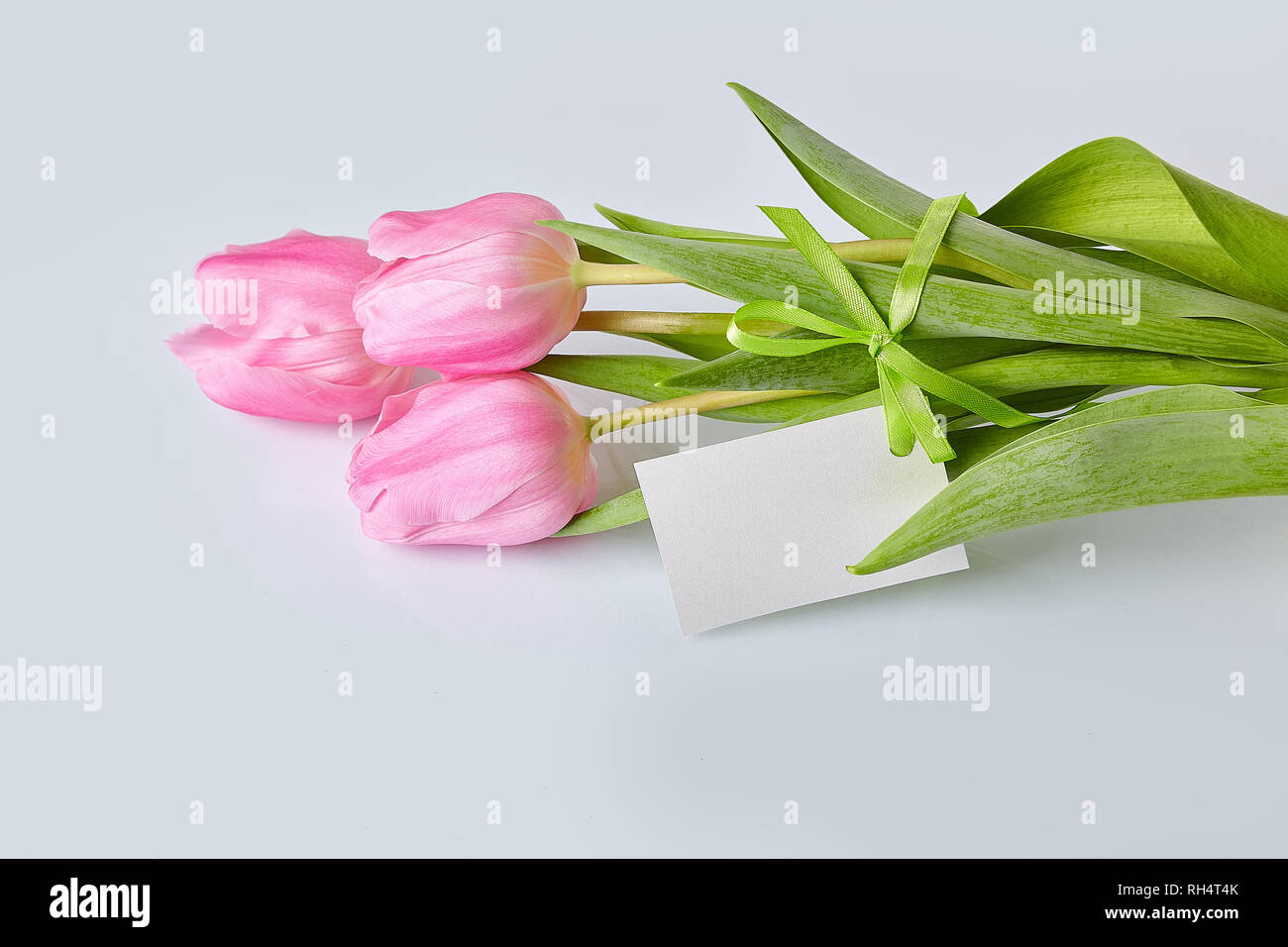 Spring flowers. Pink tulips bouquet with greeting card on a glass table ...
