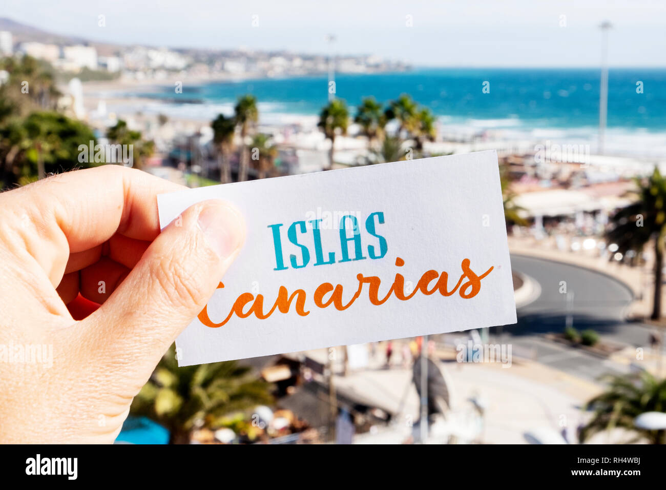 closeup of the hand of a caucasian man holding a signboard with the text Islas Canarias, Canary Islands written in Spanish, at Playa del Ingles, in Ma Stock Photo