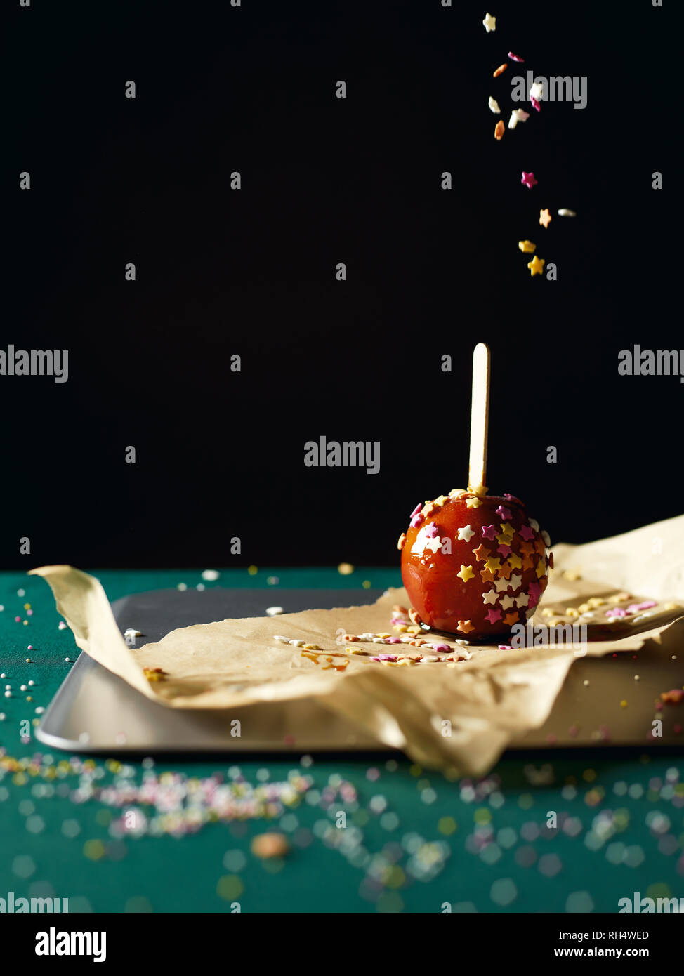 Toffee apple with sprinkles being thrown from above Stock Photo