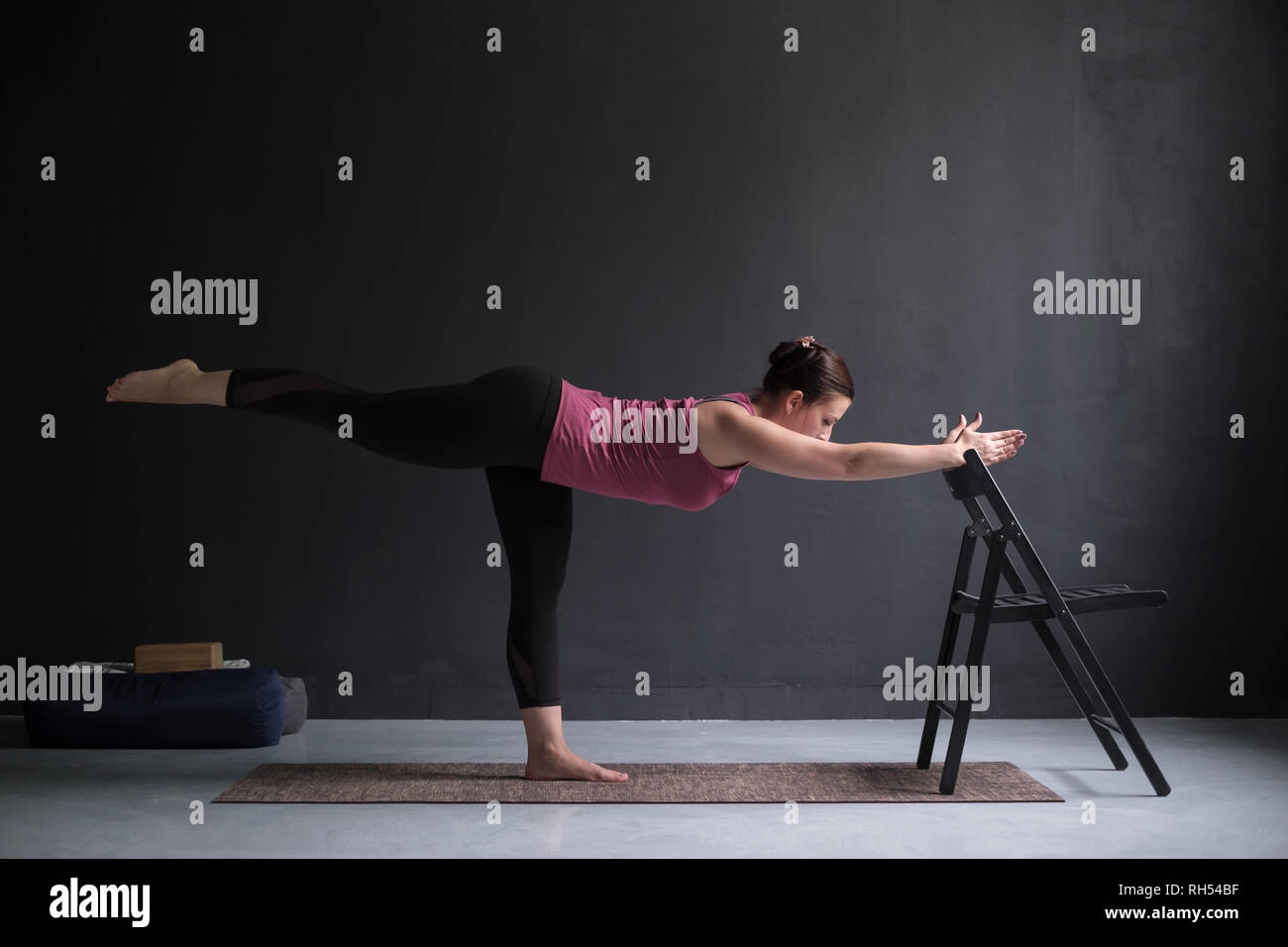 Iyengar yoga. Fit caucasian woman in purple leggings practice warrior pose  using a chair, isolated on white. Stock Photo