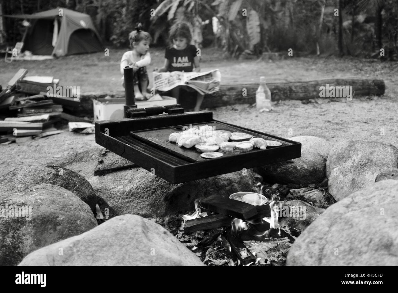 An australian style bush bbq with food cooking over a campfire with two
